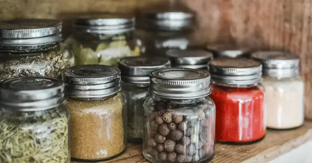 Close-up of various natural herbal supplements and draining ingredients — green tea leaves, dandelion, artichoke and horsetail plant — arranged on a wooden surface with a glass of water, soft natural lighting, health supplement concept, realistic photography