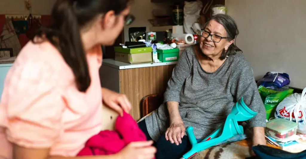 A female caregiver helping an elderly man with gentle exercises in a bright living room, both smiling, safe home environment with grab bars visible, warm and caring atmosphere, realistic stock photography