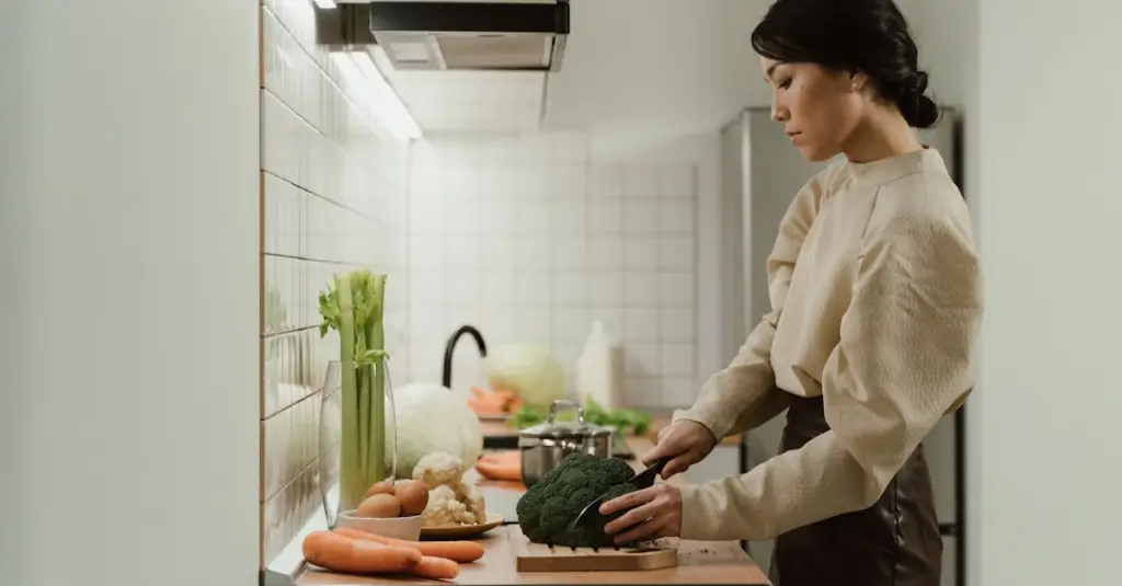 A woman preparing a healthy anti-inflammatory meal at a wooden kitchen table, surrounded by fresh salmon, colorful berries, broccoli, olive oil and turmeric, natural daylight, healthy lifestyle concept, realistic photography